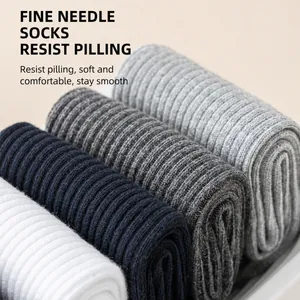 Close-up of four pairs of ribbed men's mid-calf socks in various solid neutral colors