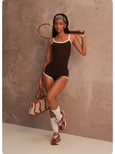 Detailed shot of a woman in a brown and white contrast yoga set with a tennis racket.