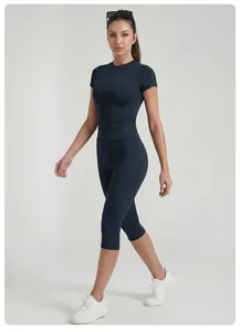 Full-body view of a woman wearing a dark blue yoga set with a short-sleeved top and capri pants.