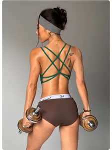Close-up back view of green strappy sports bra and brown fitness shorts with dumbbells