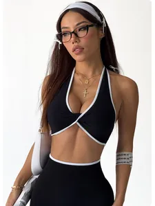 Modell trägt ein schwarzes Twist-Front-Halter-Yoga-Top mit weißen Kontrastpaspeln.