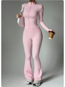 Detail of pink yoga set featuring a zip-up jacket and flared pants on a model in studio.