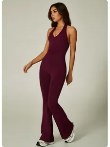 Full-body view of a model wearing a burgundy halter neck flare leg yoga jumpsuit