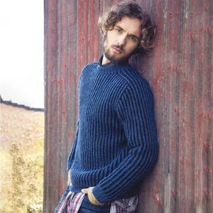 Male model wearing a blue ribbed knit crew neck sweater against a rustic wooden wall