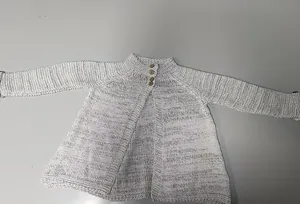 Detailopname van een wit gebreid babyvest met textuur en mooie houten knoopdetails.