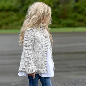 Schattig beige grof gebreid kindervest met houten knopen voor de herfst en de winter