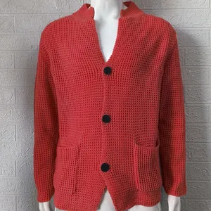 Close-up view of men's coral orange knit cardigan with waffle texture and black buttons