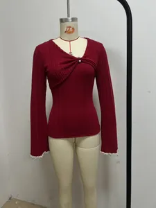 Détail d'un haut en maille côtelée rouge avec encolure asymétrique et perles blanches