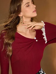 Détail de l'élégant haut en maille rouge avec encolure asymétrique et boutons en perles