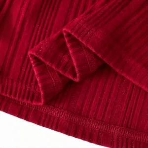Détail macro du tissu en maille côtelée rouge avec de discrets reflets scintillants chic.