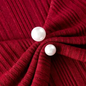 Détail rapproché exquis de boutons de perles blanches sur un tissu en maille côtelée rouge