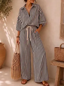 Woman wearing a stylish black and white striped shirt and wide-leg trousers set in resort style