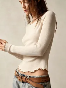 Close-up of ribbed long sleeve top with delicate ruffled hem and slim fit design