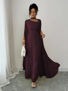 Close-up of elegant deep purple party dress with flowing cape and neck cutout.