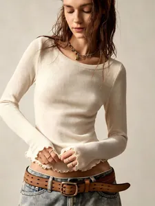 Detailed view of the ribbed fabric and lettuce edge hem on a cream slim-fit top