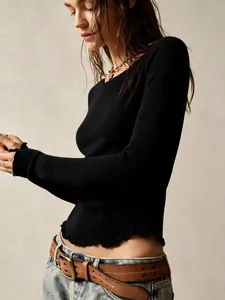 Detail view of black slim-fit long sleeve top with stylish lettuce edge hem and cuffs.
