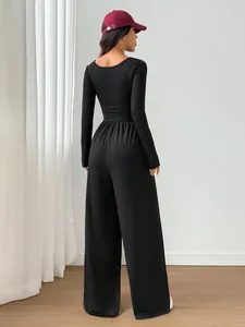 Back view of a chic black long sleeve wide leg jumpsuit with a fitted waist