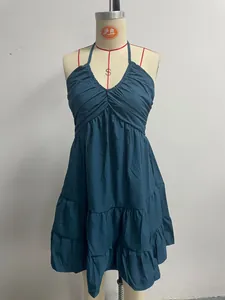 Detailed view of a teal halter neck dress featuring a ruffled hem and pleated V-neckline
