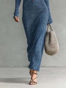 Elegant blue ribbed knit maxi dress styled with a woven straw bag and strappy sandals.