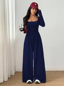 Full-length lifestyle view of a navy blue square-neck long-sleeve wide-leg jumpsuit