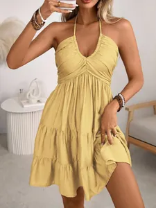 Detail of a yellow halter v-neck dress featuring a layered ruffled hem and pleated bodice.