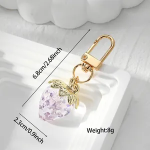 Detail view of a translucent strawberry keychain with gold finish measurements.
