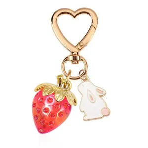 Heart-shaped gold keychain with translucent red strawberry and cute white rabbit charm