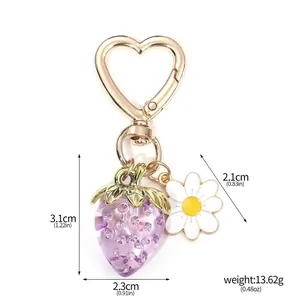 Detailed product shot of a translucent purple strawberry keychain with a daisy charm