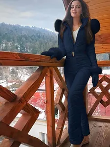 Stylish navy blue waterproof one-piece ski suit for women with fur hood on balcony