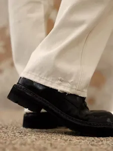 Gros plan d'un jean crème à jambe droite avec ourlet usé et chaussures à plateforme noires