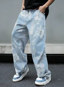 Vista dettagliata dei jeans in denim larghi da uomo con motivo floreale a rose bianche.