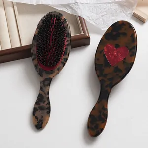 Vista detallada de un cepillo para el cabello de acetato carey con diseño de corazón rojo.