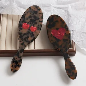 Primer plano de cepillos de acetato de carey con patrones de cereza roja y corazón.