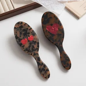 Detalle de cepillos de pelo de acetato de carey con lindos motivos de cereza y corazón