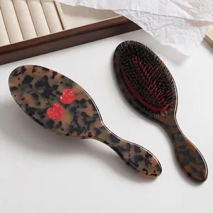 Detalle de cepillos de pelo de acetato con patrón de carey y diseño de cereza.