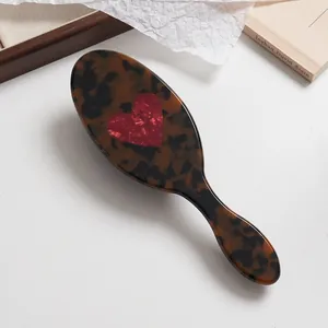 Détail d'une brosse à cheveux en écaille avec une incrustation de cœur rouge marbré