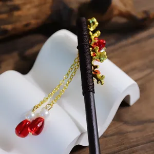 Macro detail of a traditional Chinese style tassel hair stick with red beads and golden branches