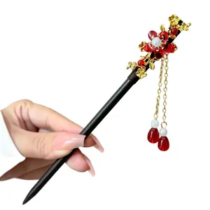 Close-up handheld view of Chinese style hair stick with red floral and tassel charms