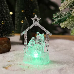 Close-up of a clear crystal Nativity scene figurine with glowing green LED light on snow