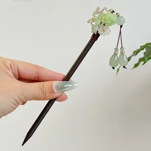 Close-up detail of a vintage Chinese style wooden hairpin with light green rose and tassels