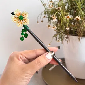 Detail of a Chinese style tassel hairpin with flower ornament and green jade-like beads.