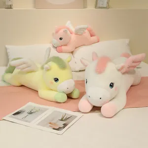 Tres adorables peluches de caballos alados en rosa, amarillo y blanco sobre una cama.