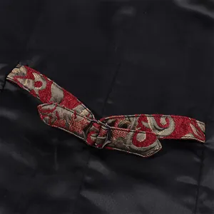 Close-up of black satin waistcoat back strap with red gold jacquard and metal buckle