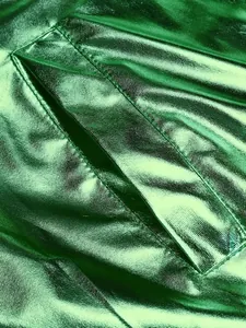 Detalle de cerca del tejido metálico verde brillante de chaqueta disco y bolsillo.