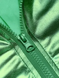 Vista detallada de la tela verde metalizada y la cremallera a juego de una chaqueta disco