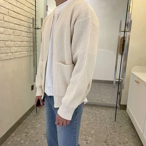 Detailed texture view of men's loose cream knit cardigan in a casual indoor setting
