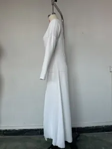 Vue latérale d'une robe longue en tricot blanc à manches longues avec fente élégante