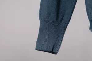 Detailed close-up of the ribbed cuff and knit texture on a dusty blue winter sweater
