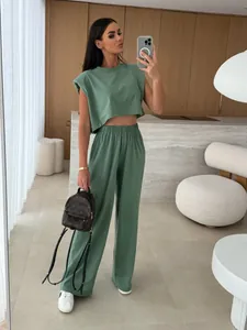 Full body view of a woman wearing a green padded shoulder top and wide-leg trousers set
