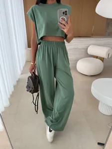 Women's green padded shoulder top and wide-leg pant set in modern home setting